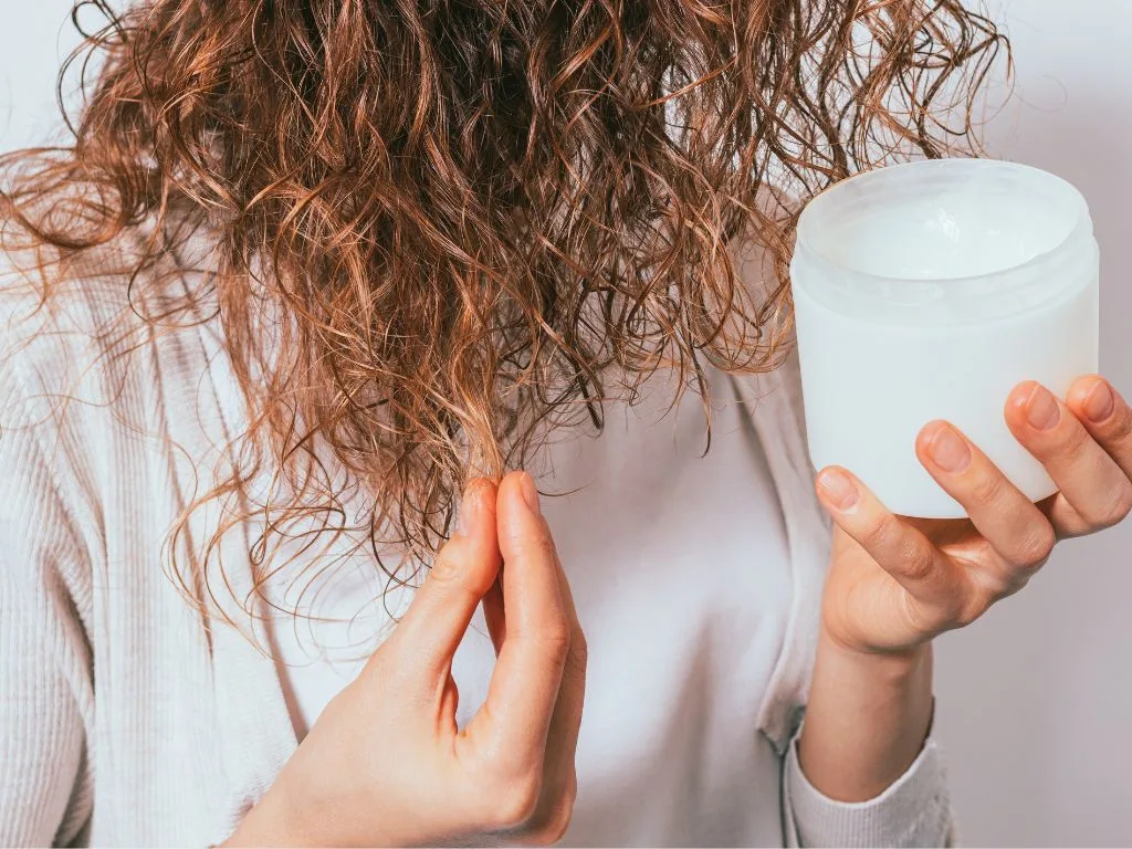 mulher aplicando óleo de coco no cabelo