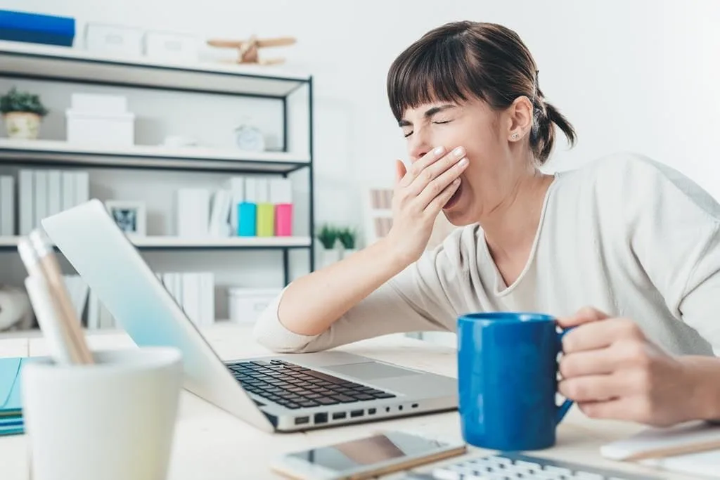 Mulher bocejando em frente ao computador
