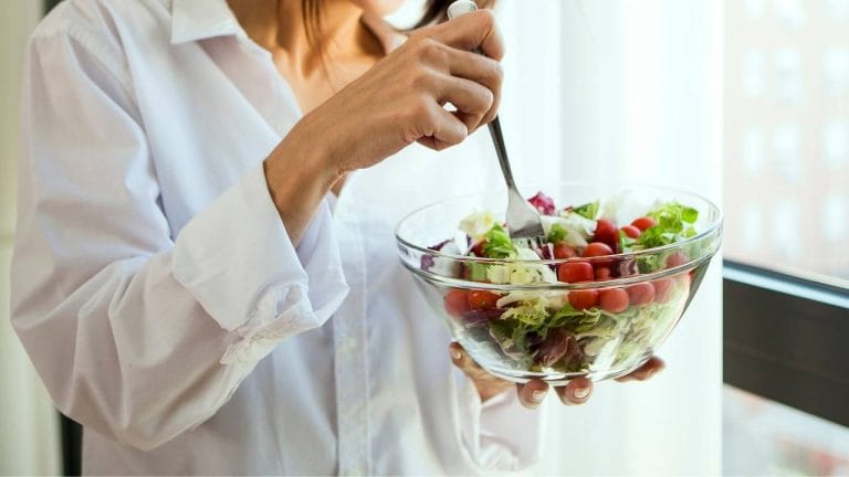 Mulher se alimentando com uma tigela de salada para melhorar a proteção do corpo.
