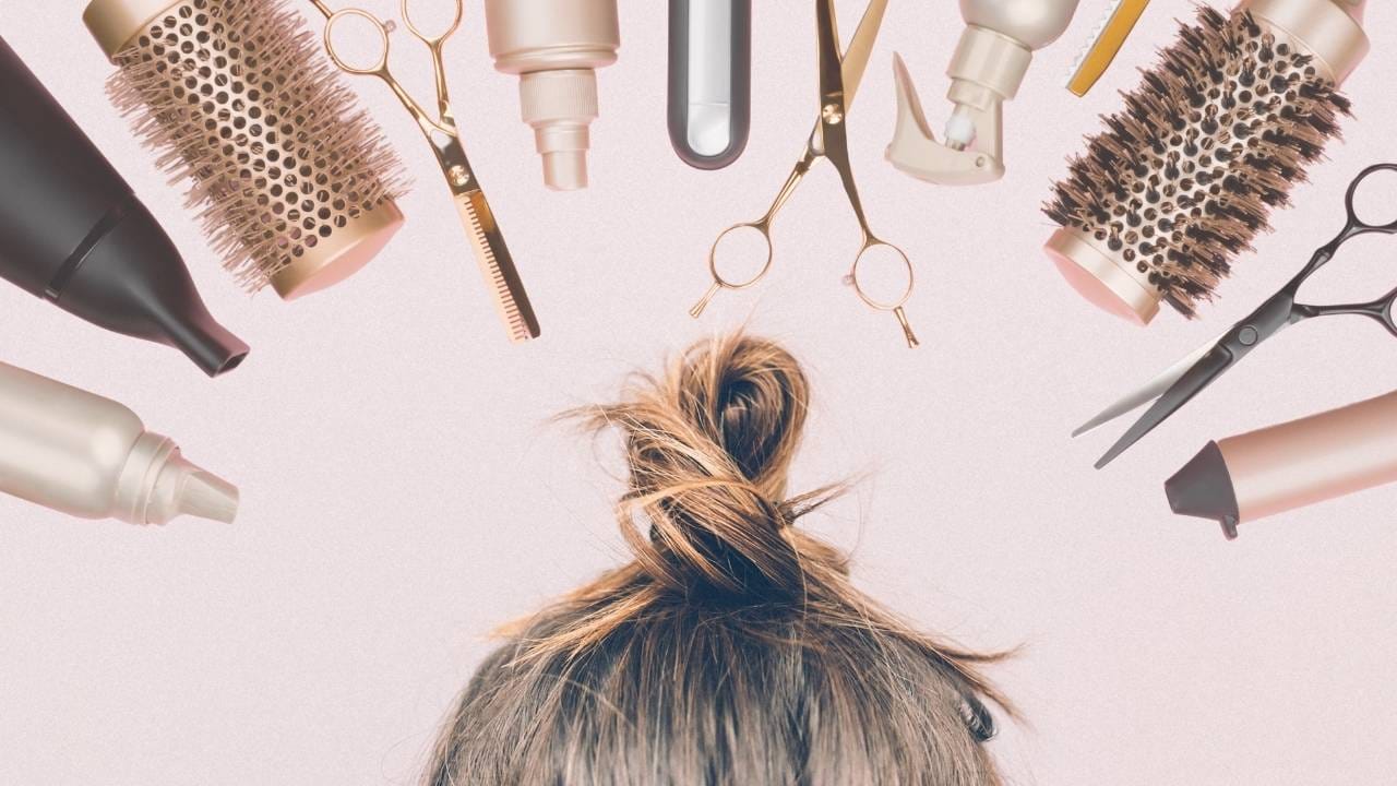 Parte de cima da cabeça de uma pessoas, com o cabelo preso e escovas, tesouras, cremes e sprays na parte superior