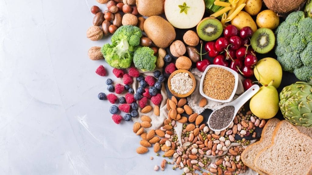 Mesa com frutas, legumes, pães e sementes essenciais para uma boa alimentação.