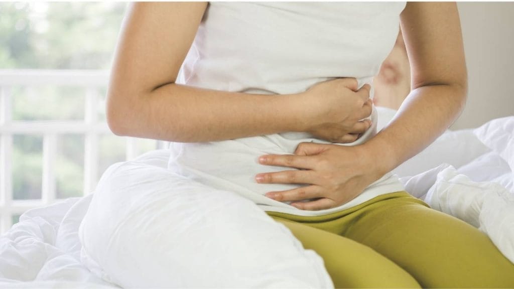 Mulher sente-se desconfortável ao sentir dores abdominais.
