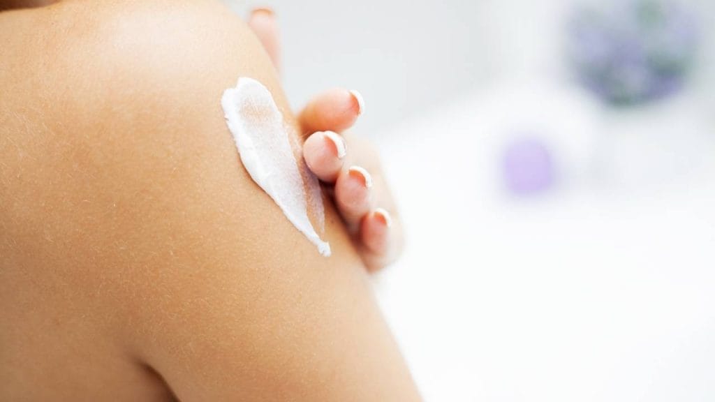 Mulher aplicando creme na pele, pós banho,