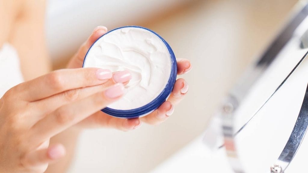 Mulher segurando um frasco de cremes hidratante, cosmético utilizado para pele.