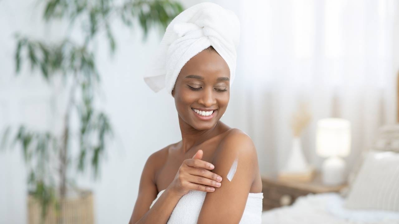 Mulher, após tomar banho, aplica em sua pele creme hidratante para evitar o ressecamento da pele.