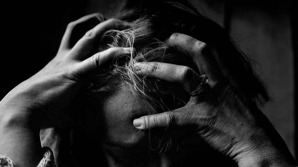 Na imagem, uma pessoa com as mãos nas cabeça, demonstrando aflição, ansiedade, causadas pela depressão.