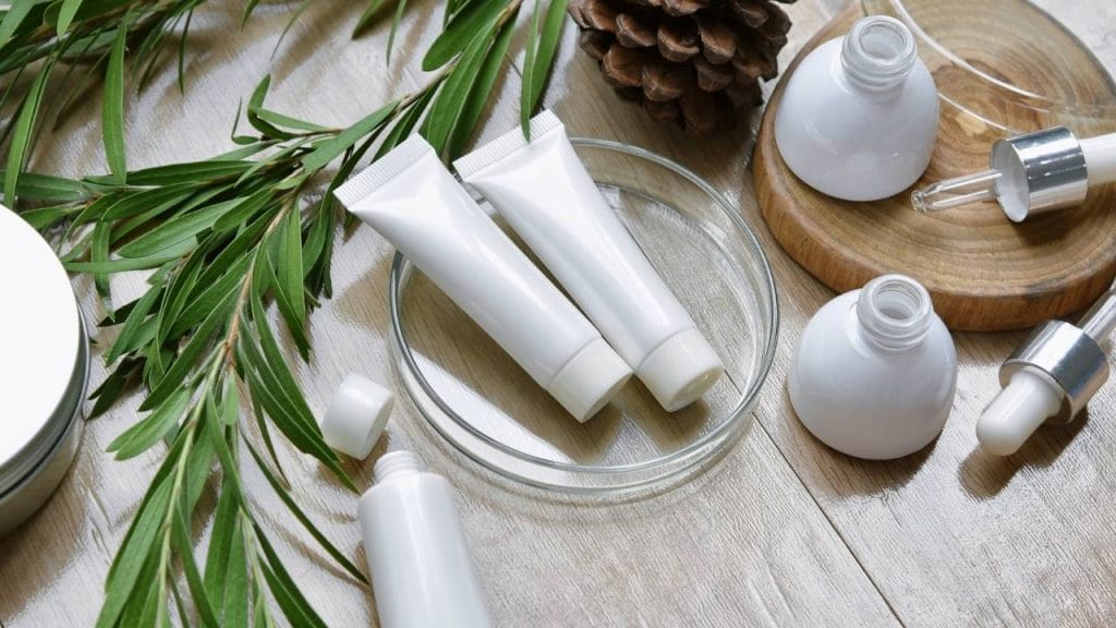 Em uma mesa, estão apoiadas algumas folhas e frascos de dermocosmético.