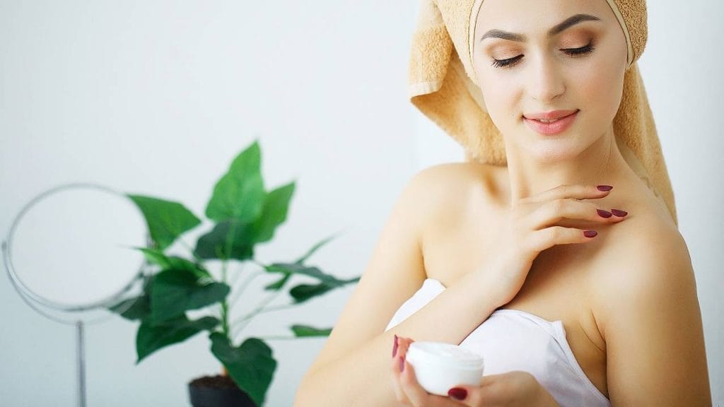 Mulher, após o banho realizando a hidratação da pele do corpo, com hidratante caseiro.