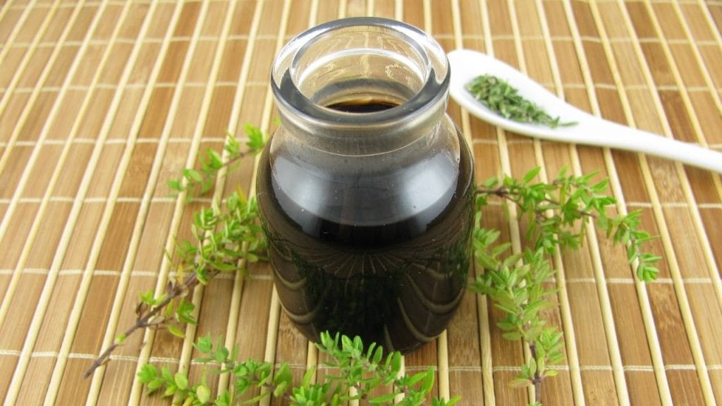 recipiente com xarope, folhas de tomilho e uma colher