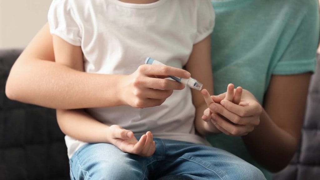 Mãe realizando a testagem de diabetes em seu filho pequeno.