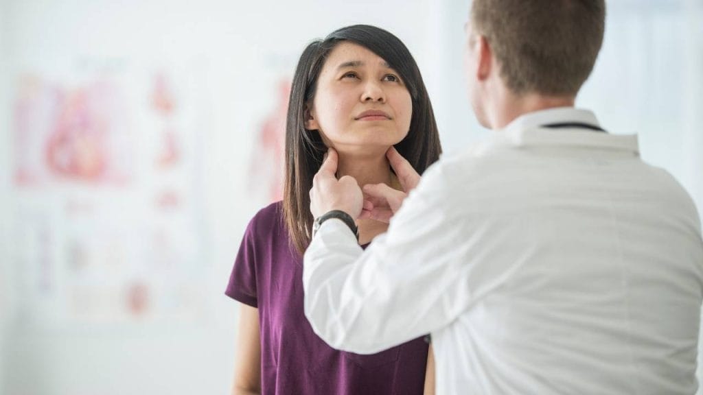 Medico avaliando as glândulas da tireoide da sua paciente, verificando a presença de alguma anomalia.