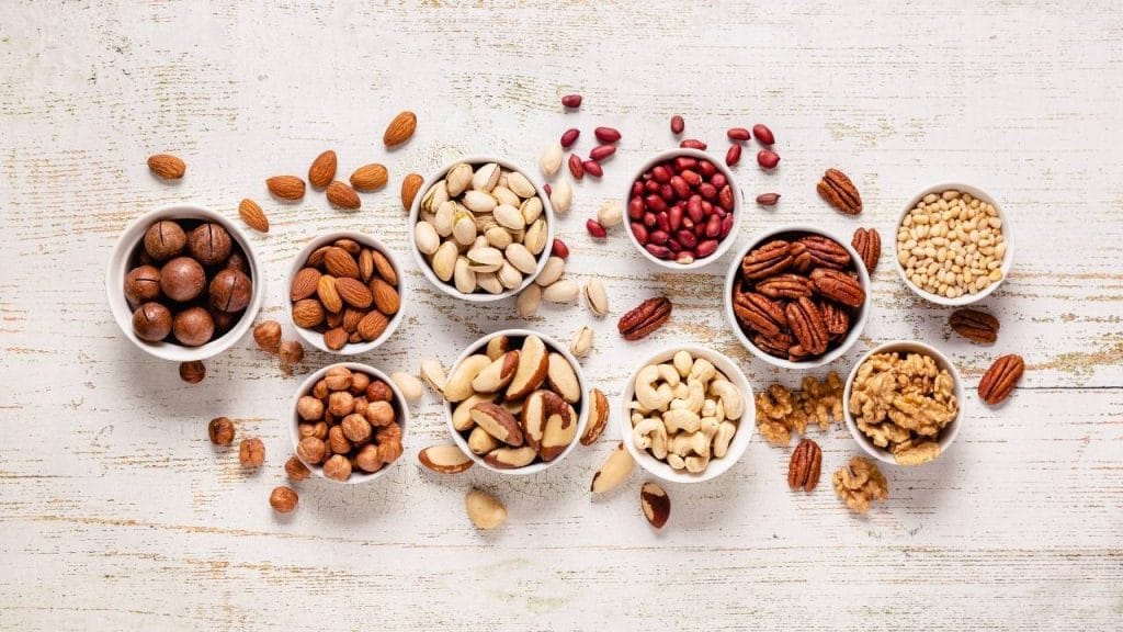 Mesa com tigelas completas com diferentes tipos de castanhas.