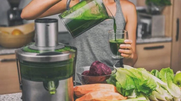Mulher fazendo suco para aumentar imunidade com vegetais.