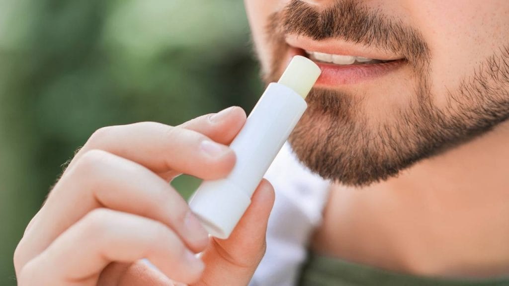 Homem realizando a hidratação dos lábios com protetor labial.