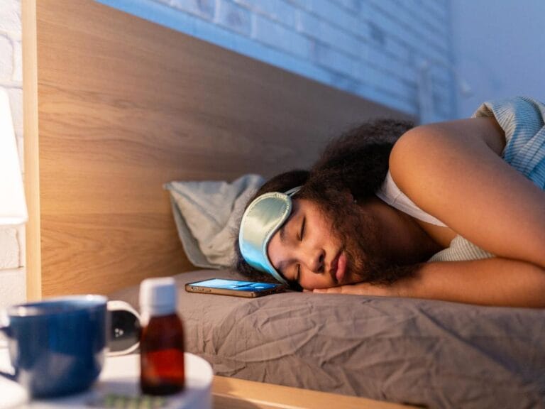 Mulher dormindo com remédio para reposição de melatonina ao lado da cama