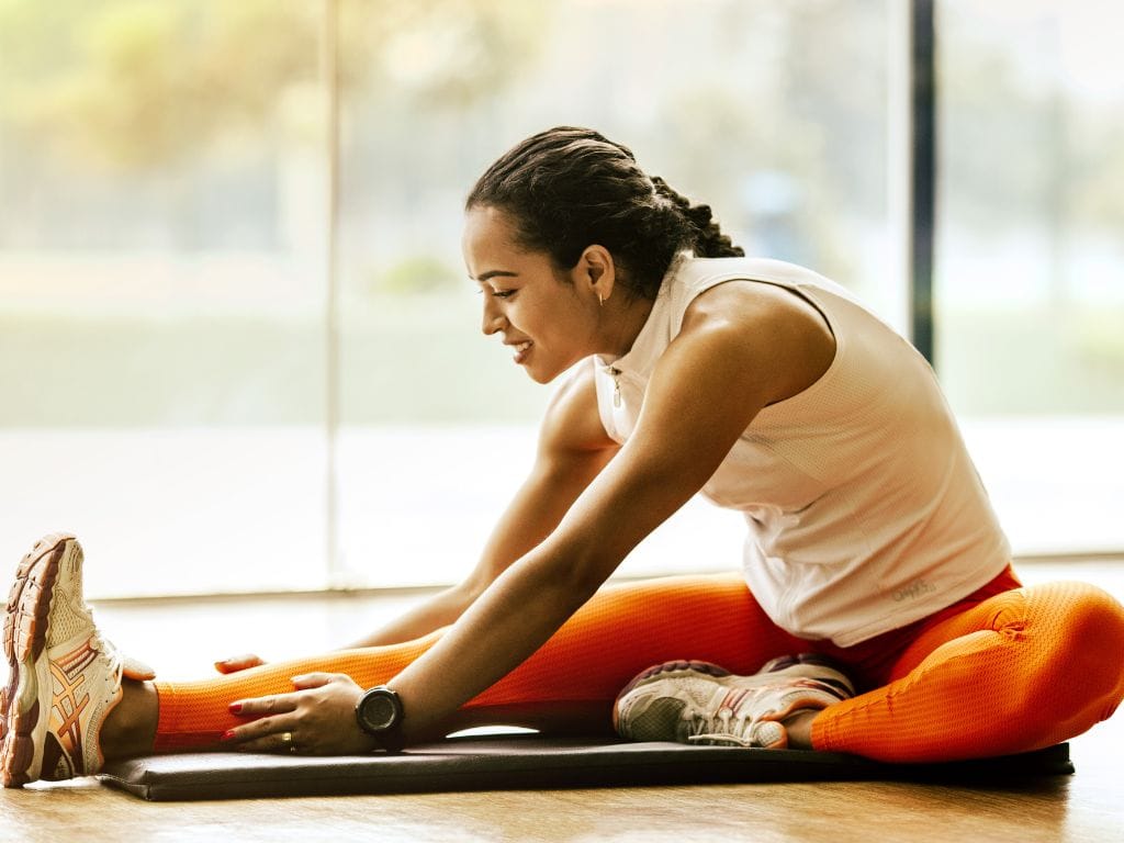 mulher fazendo alongamento antes do treino de hipertrofia
