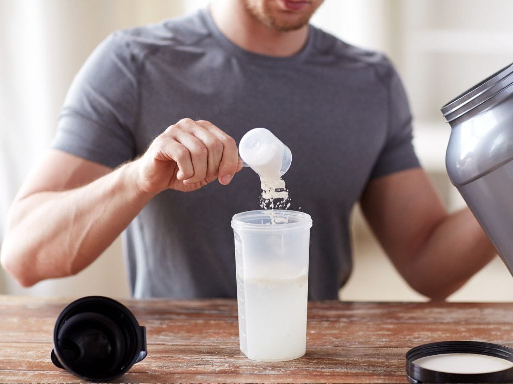 homem colocando whey protein em um pote