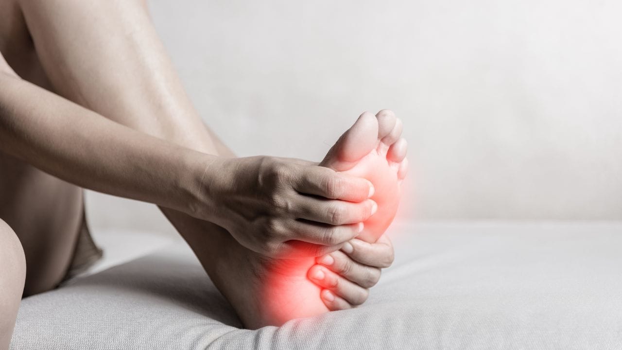 pessoa segurando o pé com dor de fascite plantar