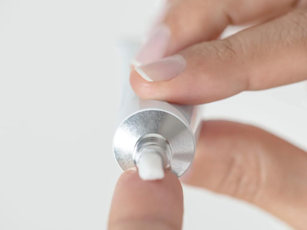 pessoa segurando embalagem de pomada